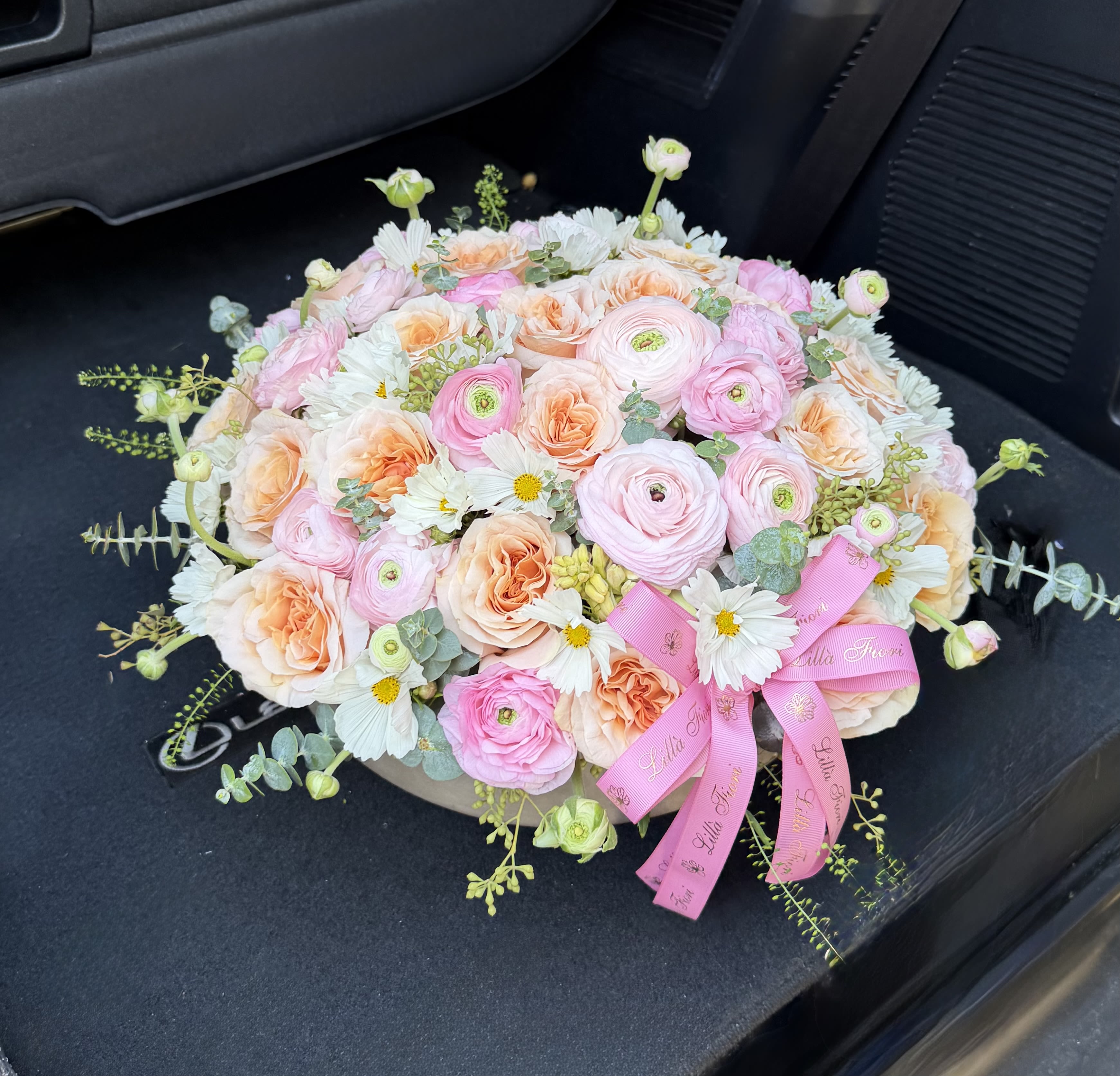 Round bouquet of pink and peach flowers with a pink ribbon