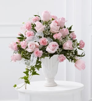 Pink roses and carnations arranged in a white vase