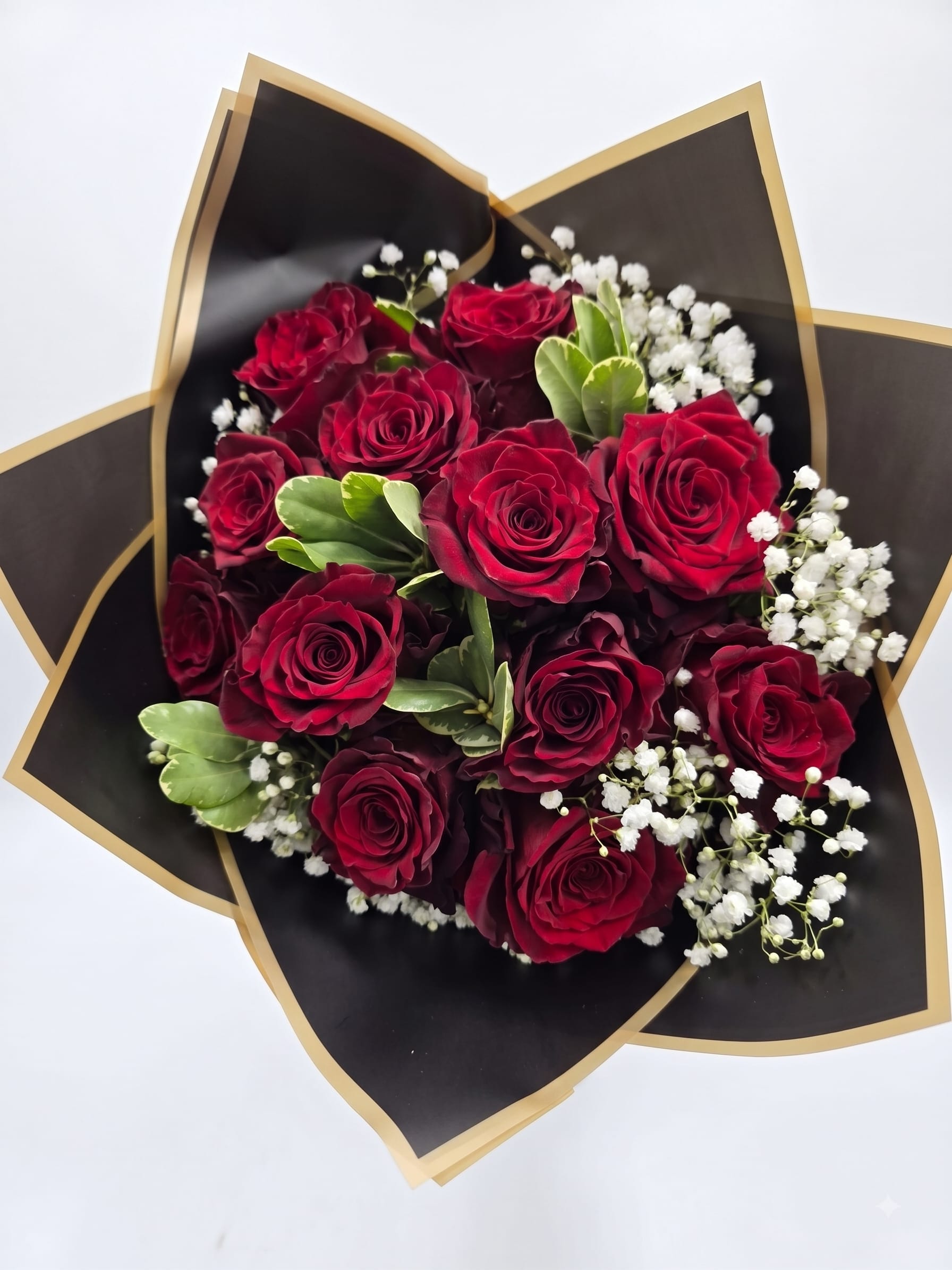 Bouquet of red roses with white baby's breath in black and gold wrap