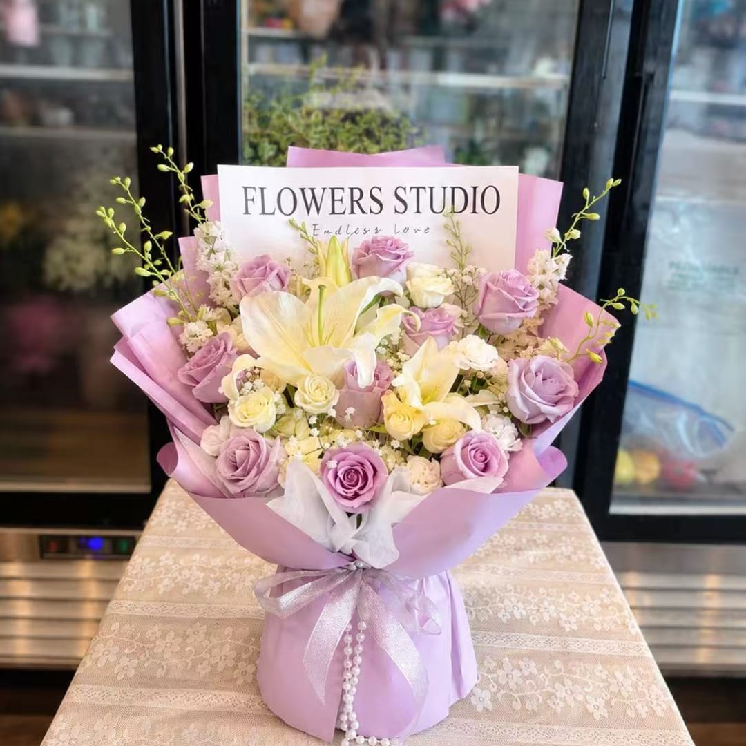 Lavender and white bouquet with roses and lilies wrapped in pink paper