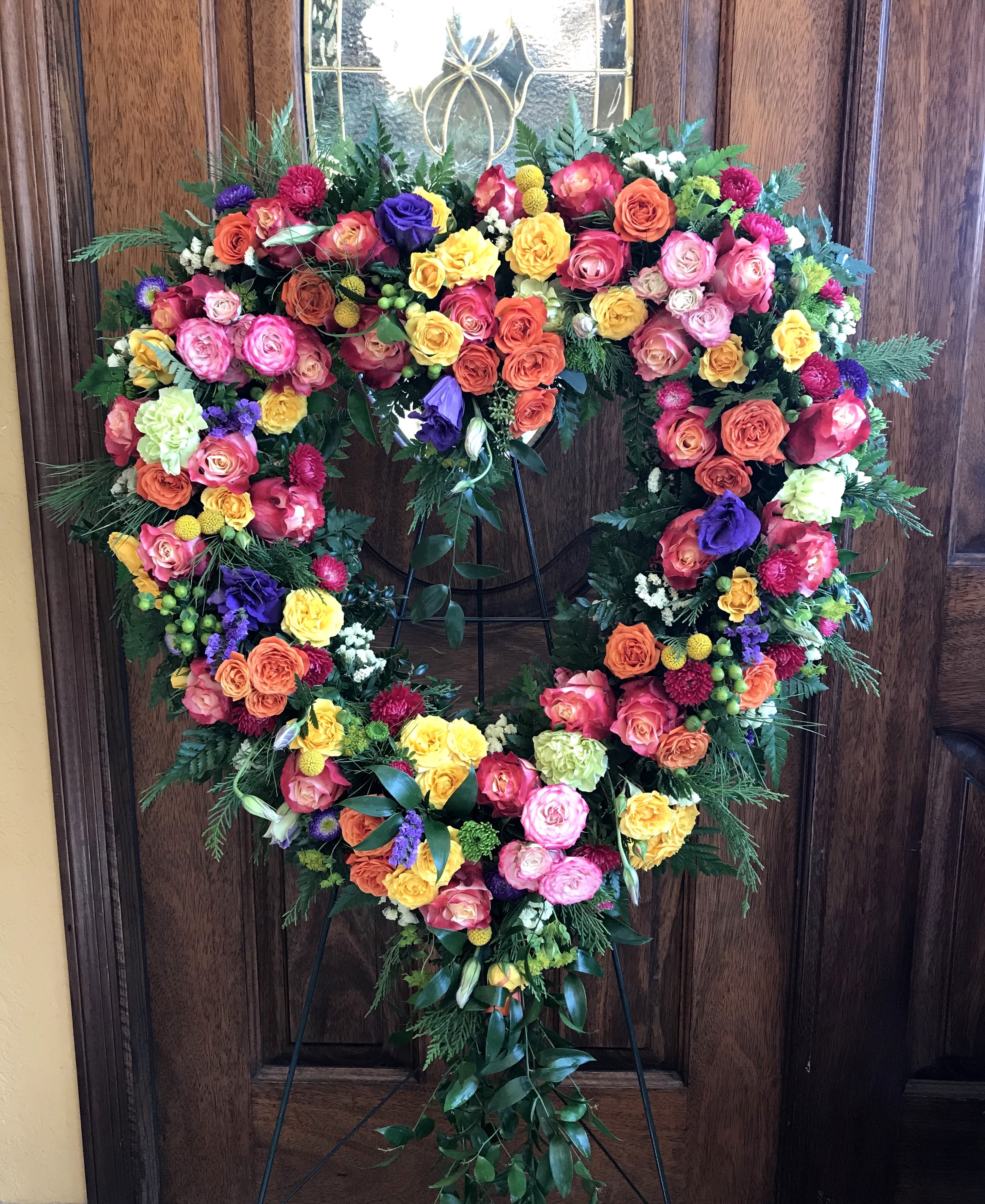 Heart-shaped floral wreath on a stand with multicolored roses