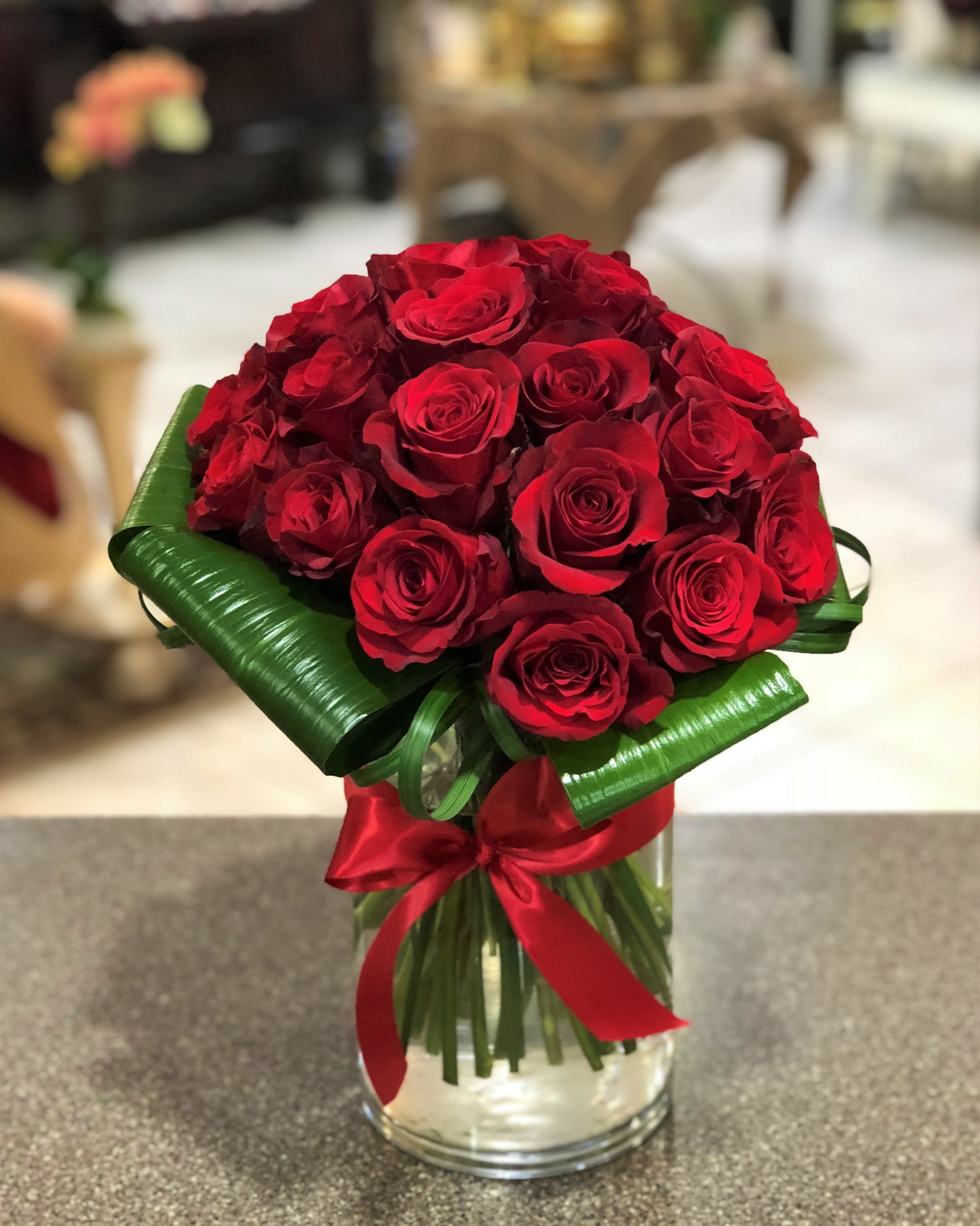 Bouquet of red roses in a glass vase with a red ribbon