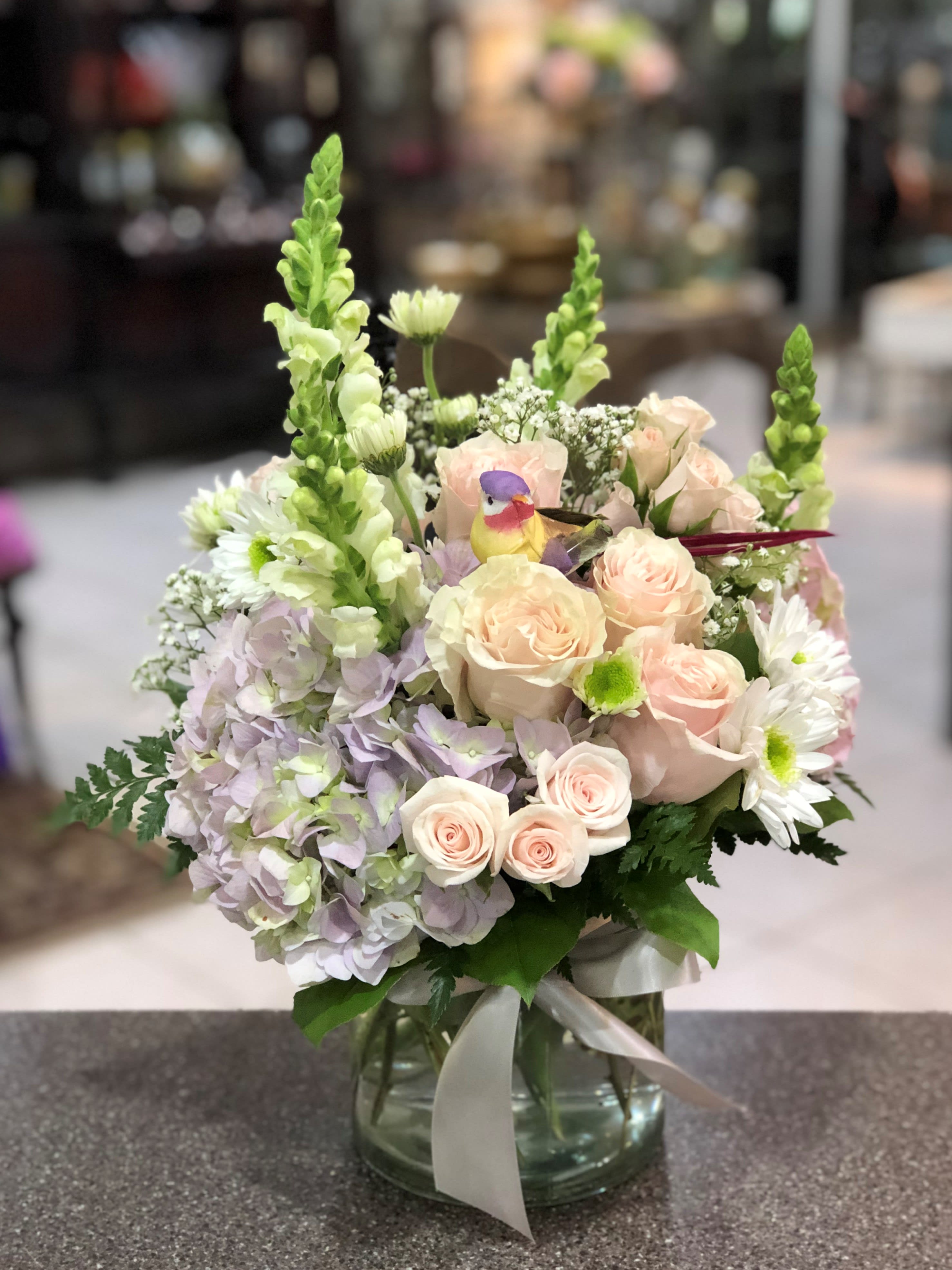 Pastel flower arrangement in a glass vase with roses, hydrangeas, and daisies