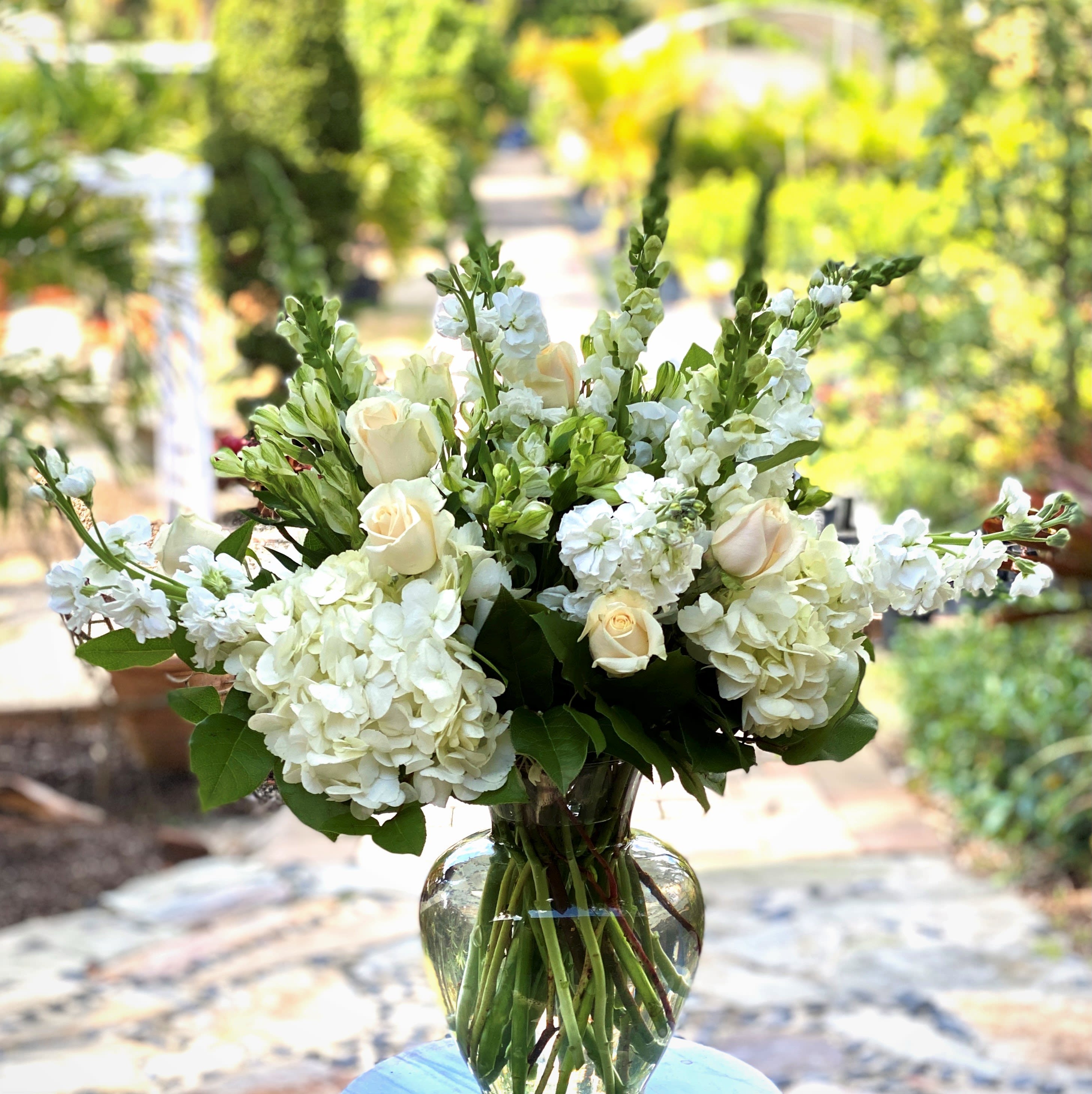 White roses and hydrangeas arranged in a clear glass vase