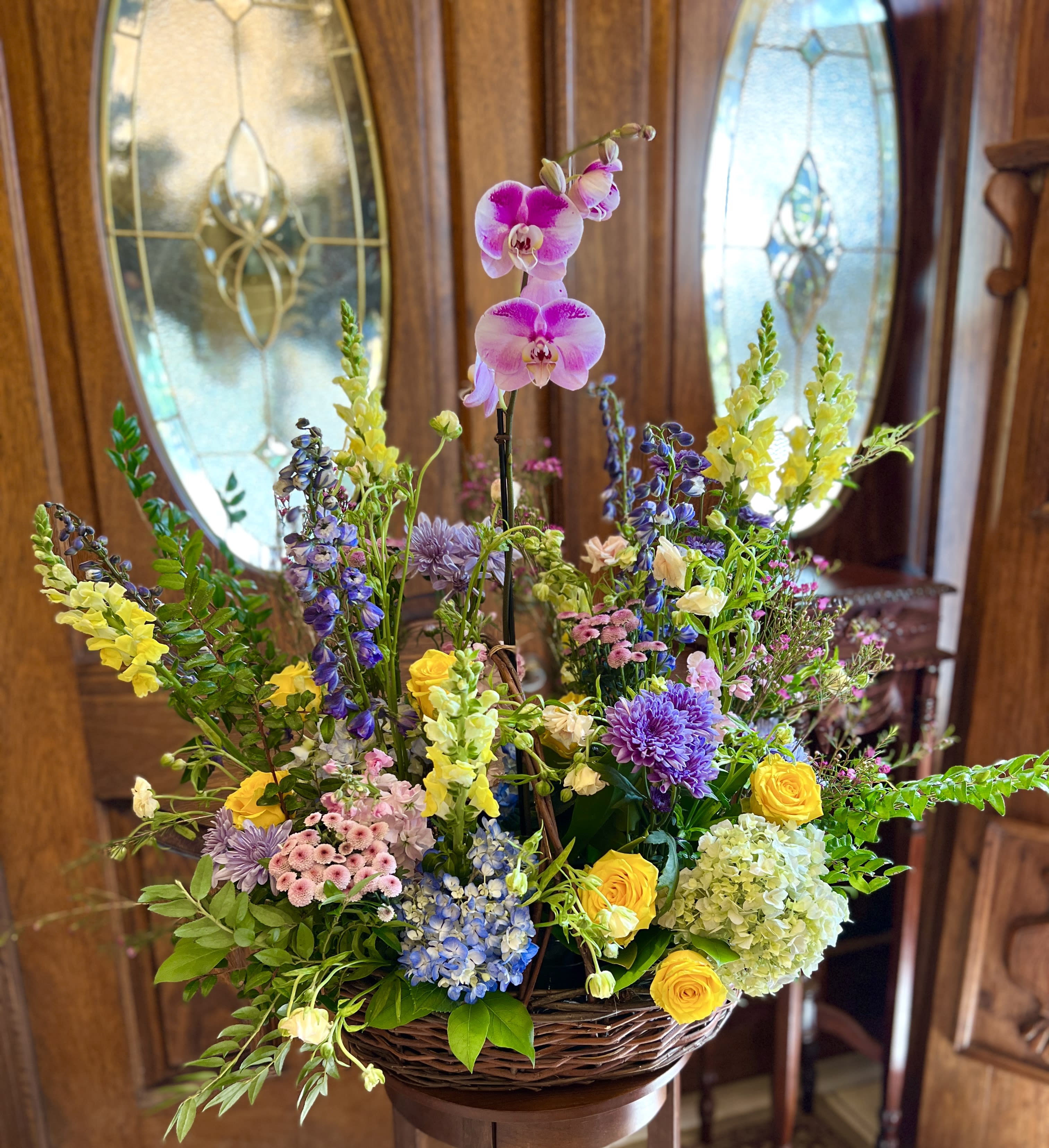 Large basket arrangement with orchids, roses, hydrangeas, and mixed blooms