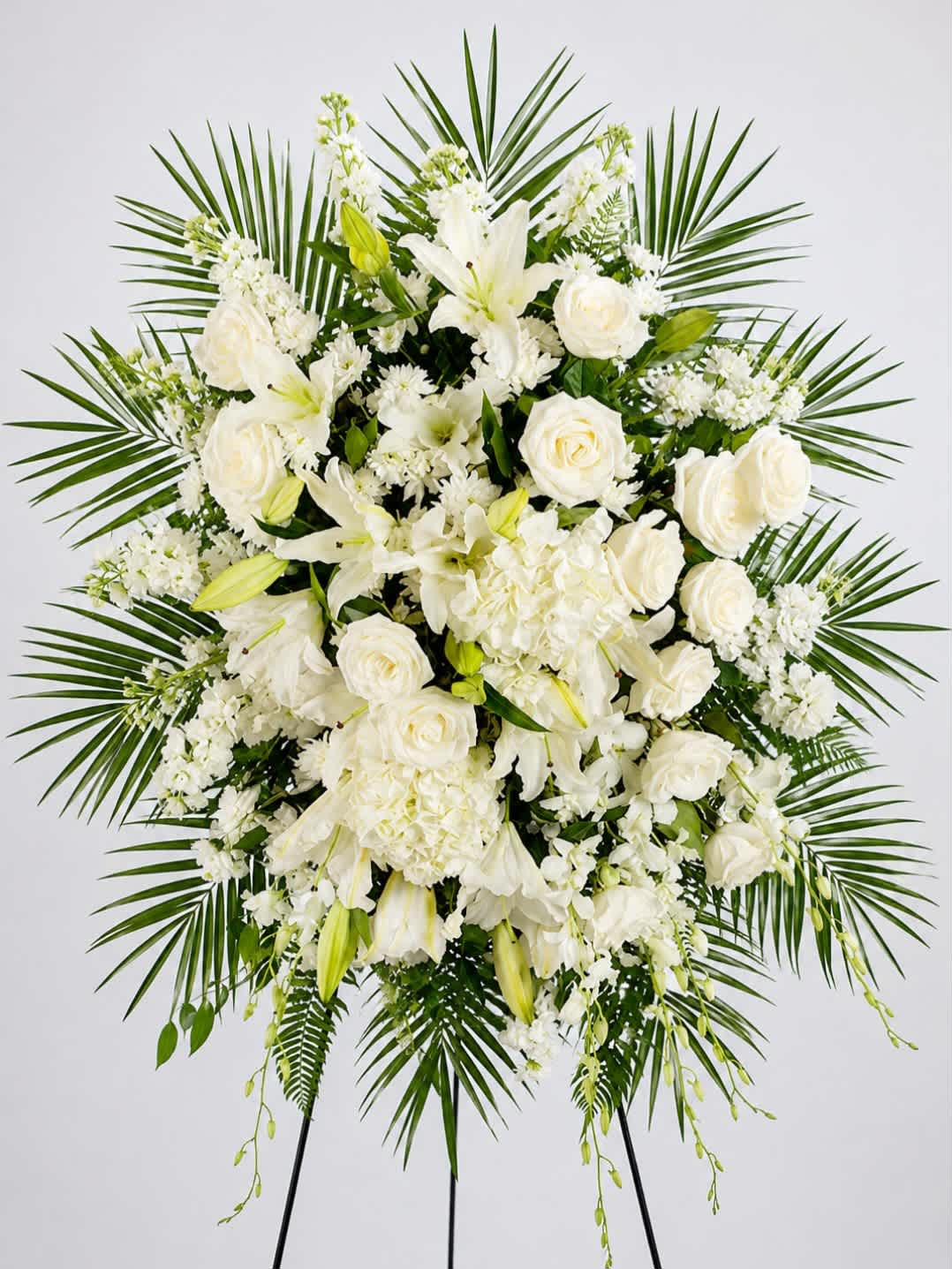 White floral standing spray with roses, lilies, and palm fronds