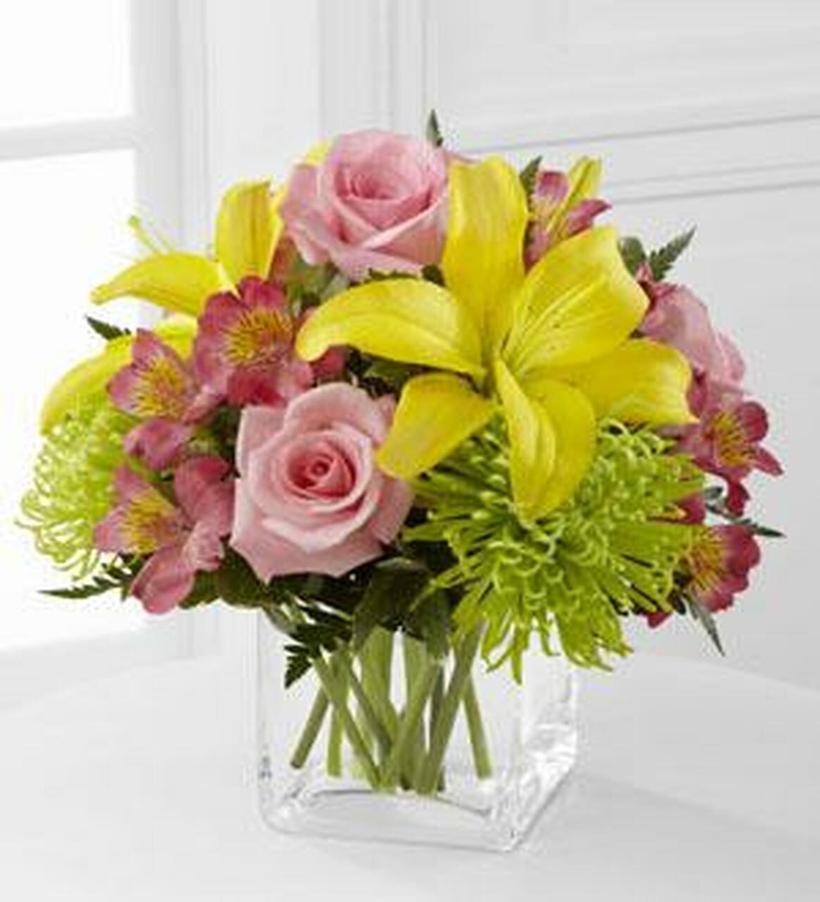 Pink roses and yellow lilies in a clear glass vase