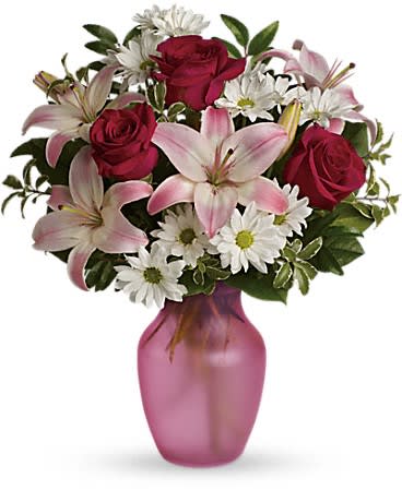 Bouquet of pink lilies, red roses, and white daisies in a pink vase