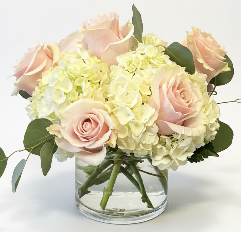 Blush roses and pale hydrangeas in a clear glass vase