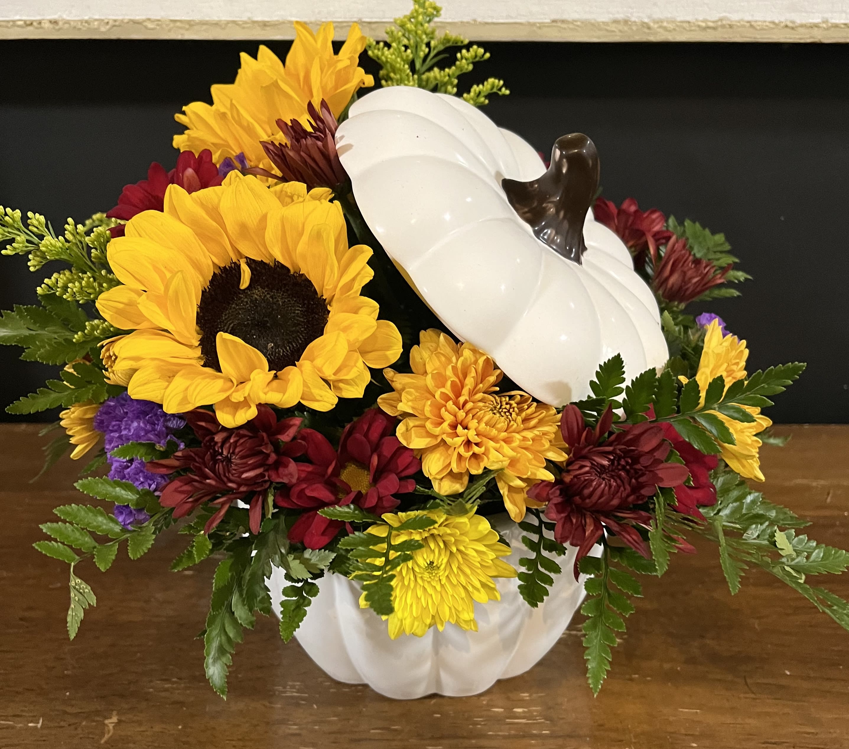 Sunflowers and chrysanthemums arranged in a white pumpkin container