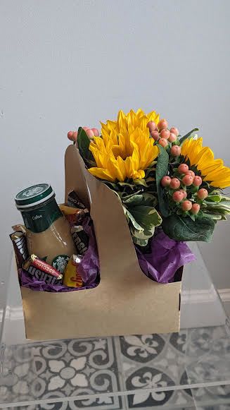 Sunflower bouquet with berries and a coffee cup in a gift box