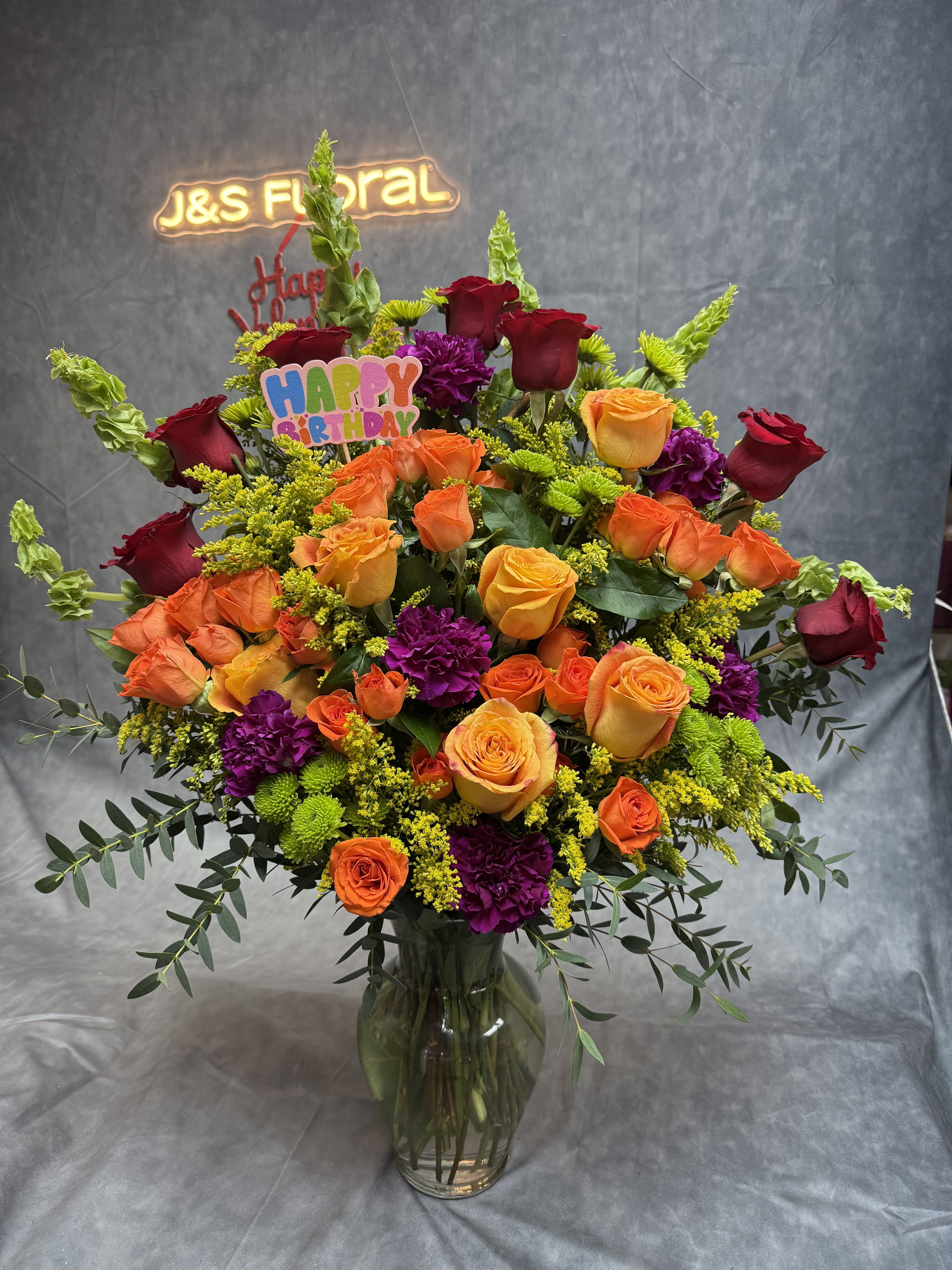 Large mixed bouquet of roses, carnations, and greenery in a glass vase