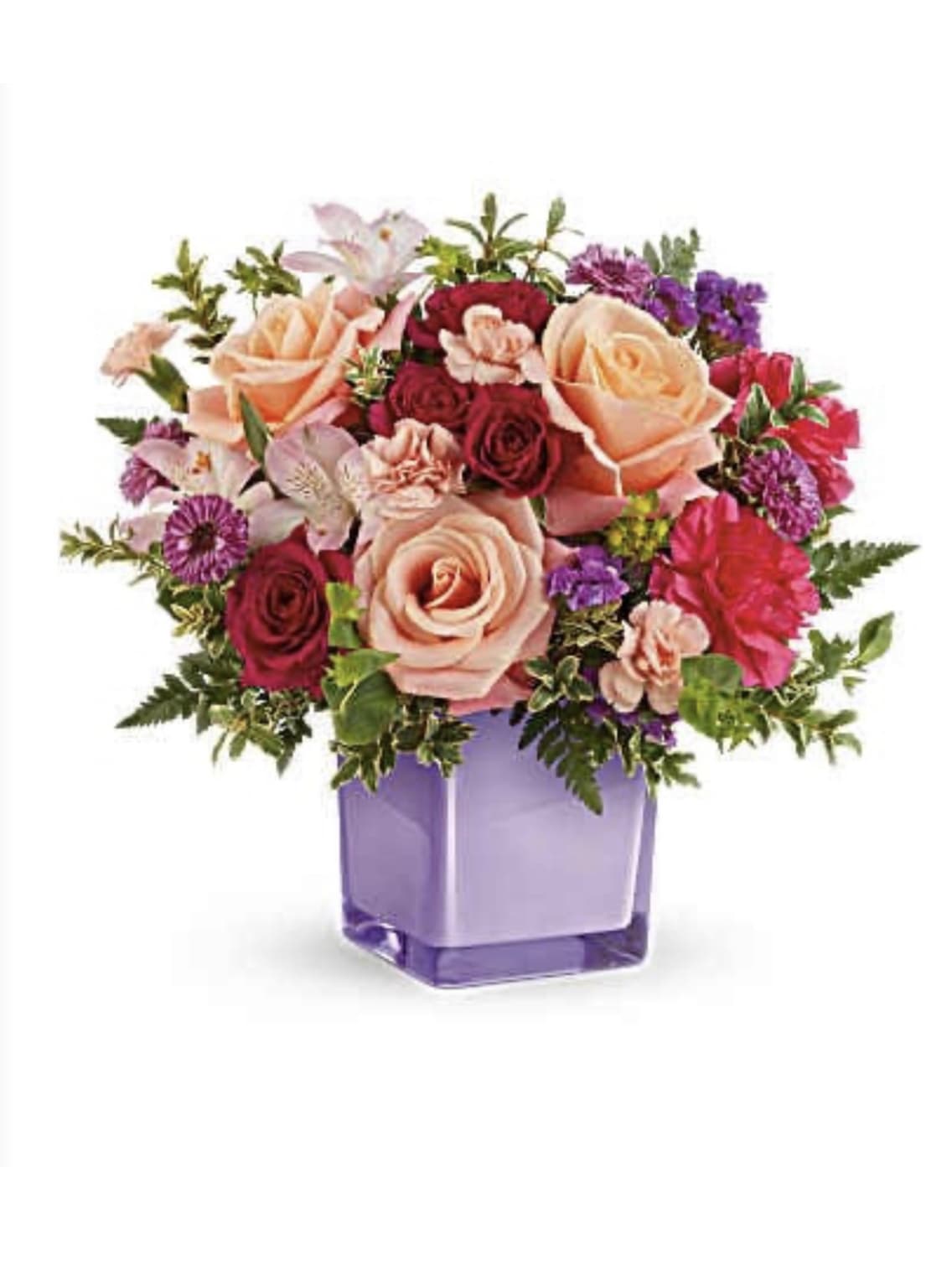  PEACH BIRTHDAY  BOUQUE - Peach roses and a lively mix of pink, red, purple, and white blooms make this birthday bouquet a joyful, celebratory gift that reads as both romantic and cheerfully upbeat. Designed as a birthday arrangement that also suits get-well wishes or Women's Day, the composition greets the person you're thinking of with warm color and a generous, rounded shape that feels comforting and uplifting.  A dense cluster of large peach roses anchors the design, surrounded by smaller roses, ruffled carnations, alstroemeria and lily-style blooms for texture and movement. The flowers are arranged full and close together in a square purple glass vase, the cool violet container heightening the warmth of the peach and pink tones for a striking contrast. The overall look is vibrant but harmonious-soft petals, varied shapes, and a pleasing mix of heights that read beautifully from every angle.  Perfect for sending someone a bright pick-me-up or marking a special birthday, this arrangement arrives ready to display in its glass vase. Recommend refreshing the water every 2-3 days and trimming stems slightly to extend vase life so the recipient enjoys the cheerful display longer.