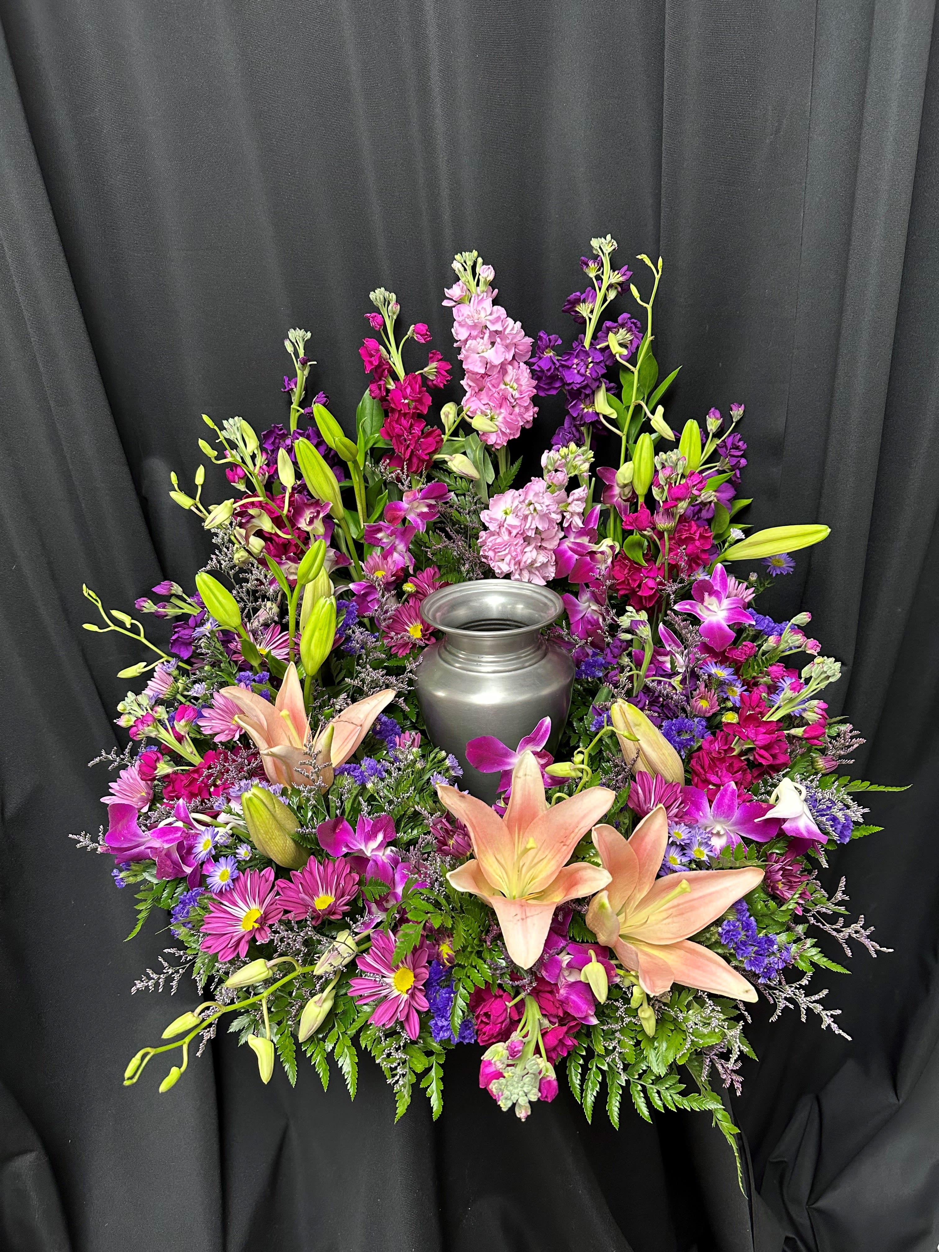 Colorful floral wreath around a silver urn on black drape