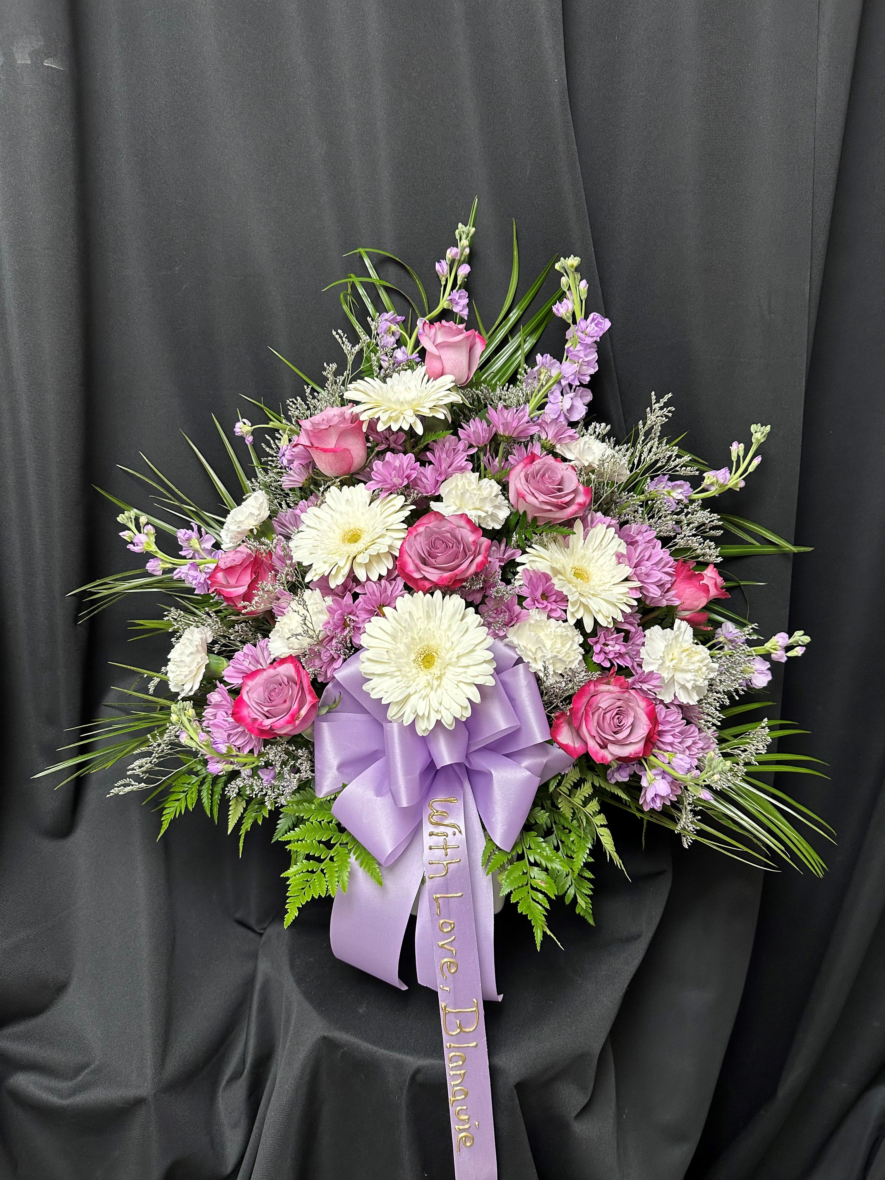 Pink and white floral spray with a lavender ribbon on black fabric
