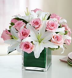 Pink roses and white lilies arranged in a clear square vase