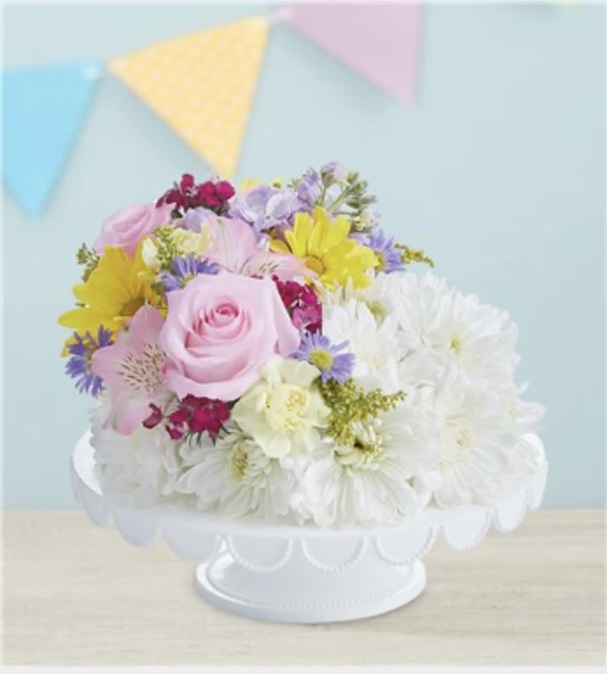 Pastel mixed flower arrangement in a white pedestal bowl