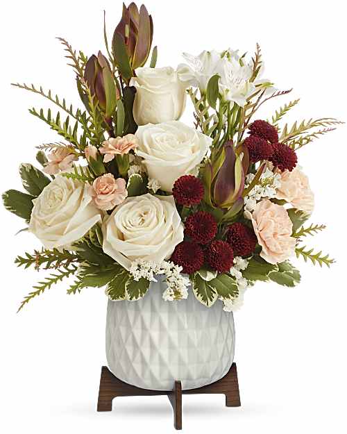 White roses and burgundy flowers in a white vase on a wooden stand