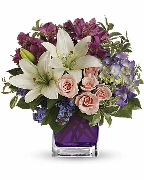 Garden Lovely  - Va-va-bloom! This grand array of purple hydrangea, light pink spray roses and white asiatic lilies is presented in our violet cube. hydrangea, light pink spray roses, white asiatic lilies, dark pink alstroemeria and lavender sinuata statice are accented with assorted greens. Delivered in Teleflora's glass violet cube. Orientation: All-Around