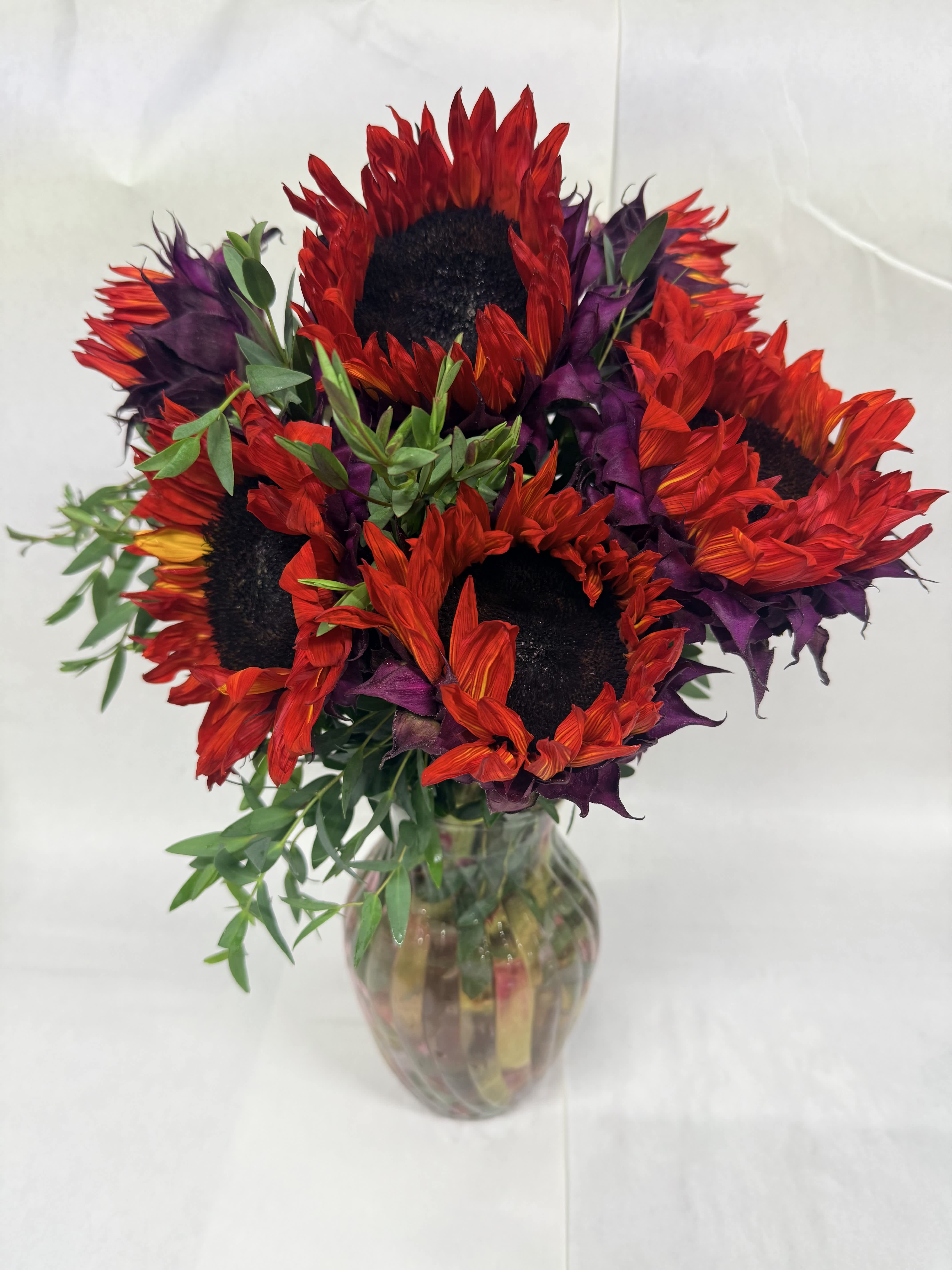 Bouquet of red and purple sunflowers in a glass vase