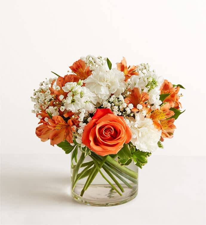 Orange and white flower arrangement in a clear glass vase