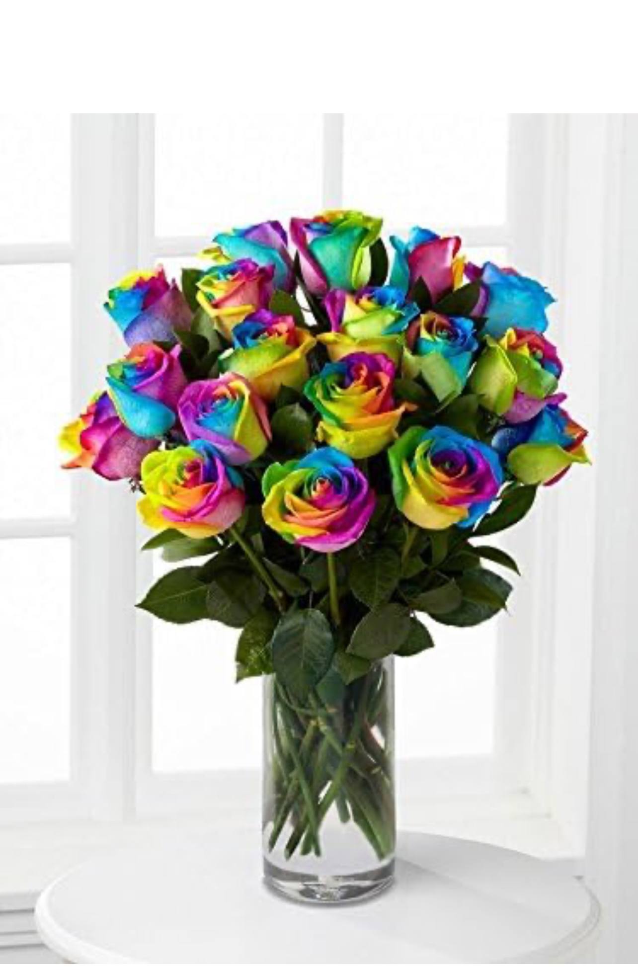Rainbow-colored roses in a clear glass vase