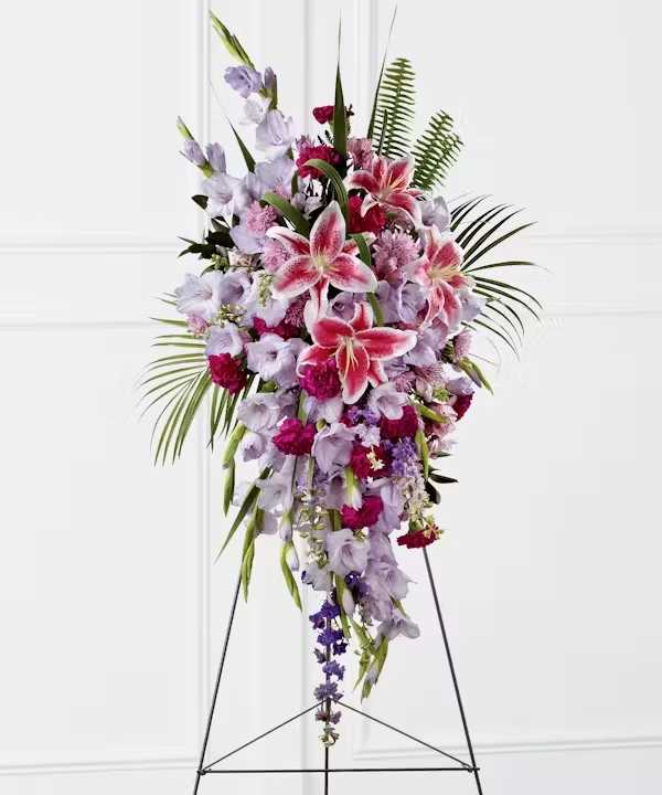 The Tender Touch Standing Spray - The Tender Touch Standing Spray creates an elegant display of beauty and color to enhance their final tribute. Lavender gladiolus, Stargazer lilies, fuchsia carnations, purple larkspur, lavender Peruvian lilies, lavender chrysanthemums, sword fern fronds, emerald palm fronds and other assorted greens are gorgeously arranged to create a sophisticated standing spray. Displayed on a wire easel, this arrangement will add to the sophistication of their service with each fragrant bloom.