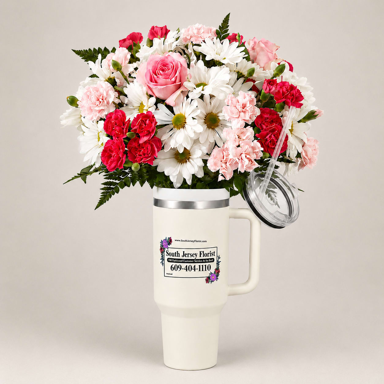 Bouquet of pink roses, carnations, and white daisies in a handled tumbler cup