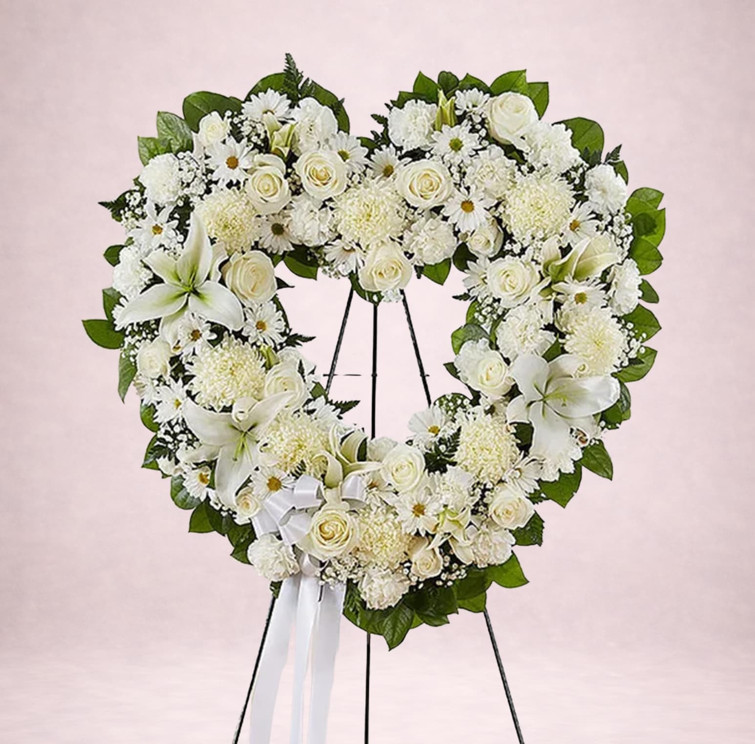 Heart-shaped white floral wreath on a stand with a ribbon bow