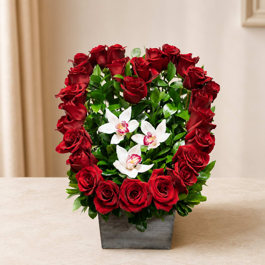 Red roses arranged around white orchids in a square gray vase