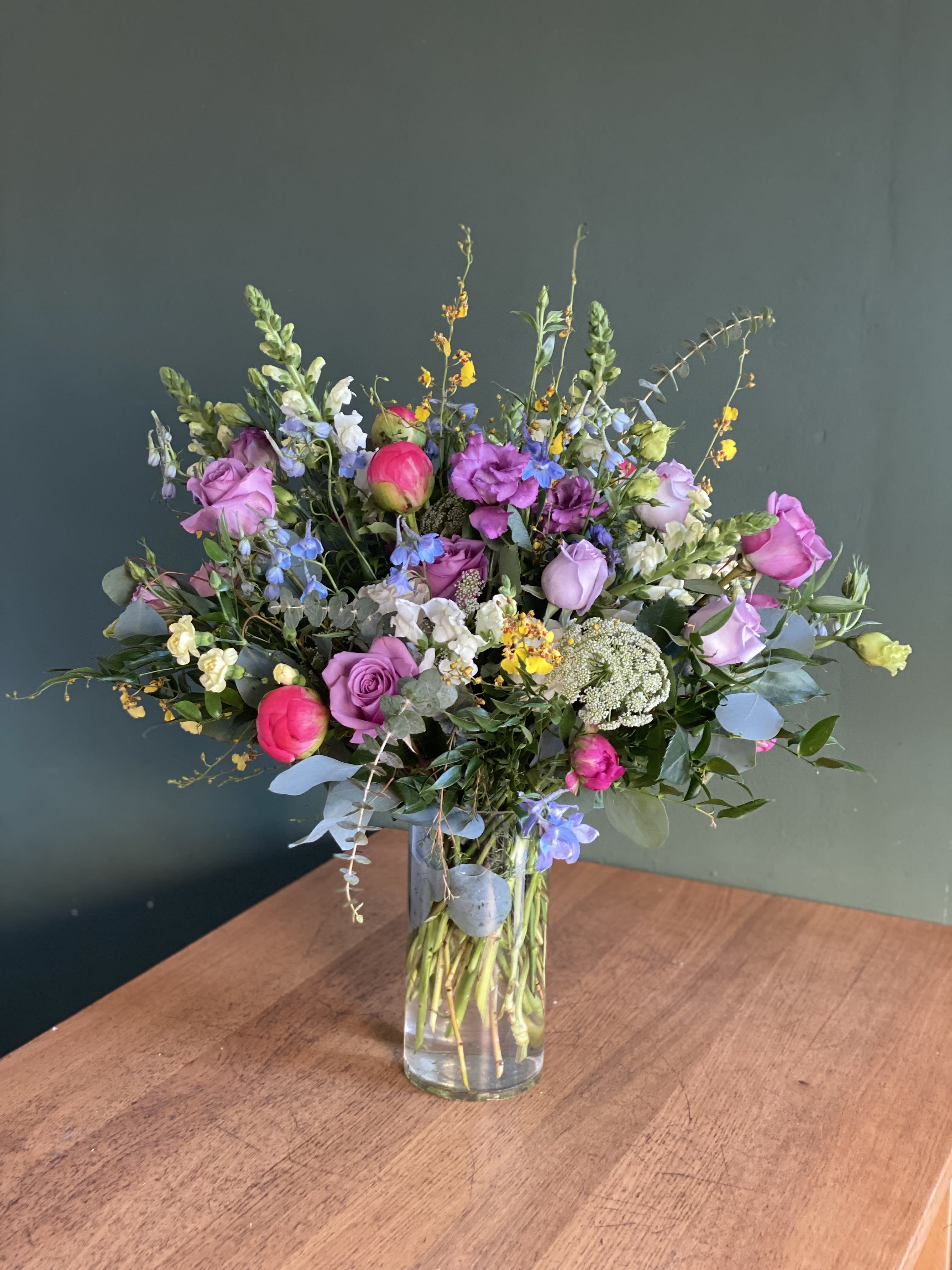 Mixed bouquet of pink and purple flowers in a clear glass vase