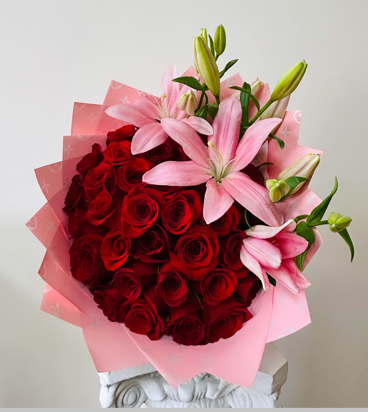 Bouquet of red roses and pink lilies wrapped in pink paper