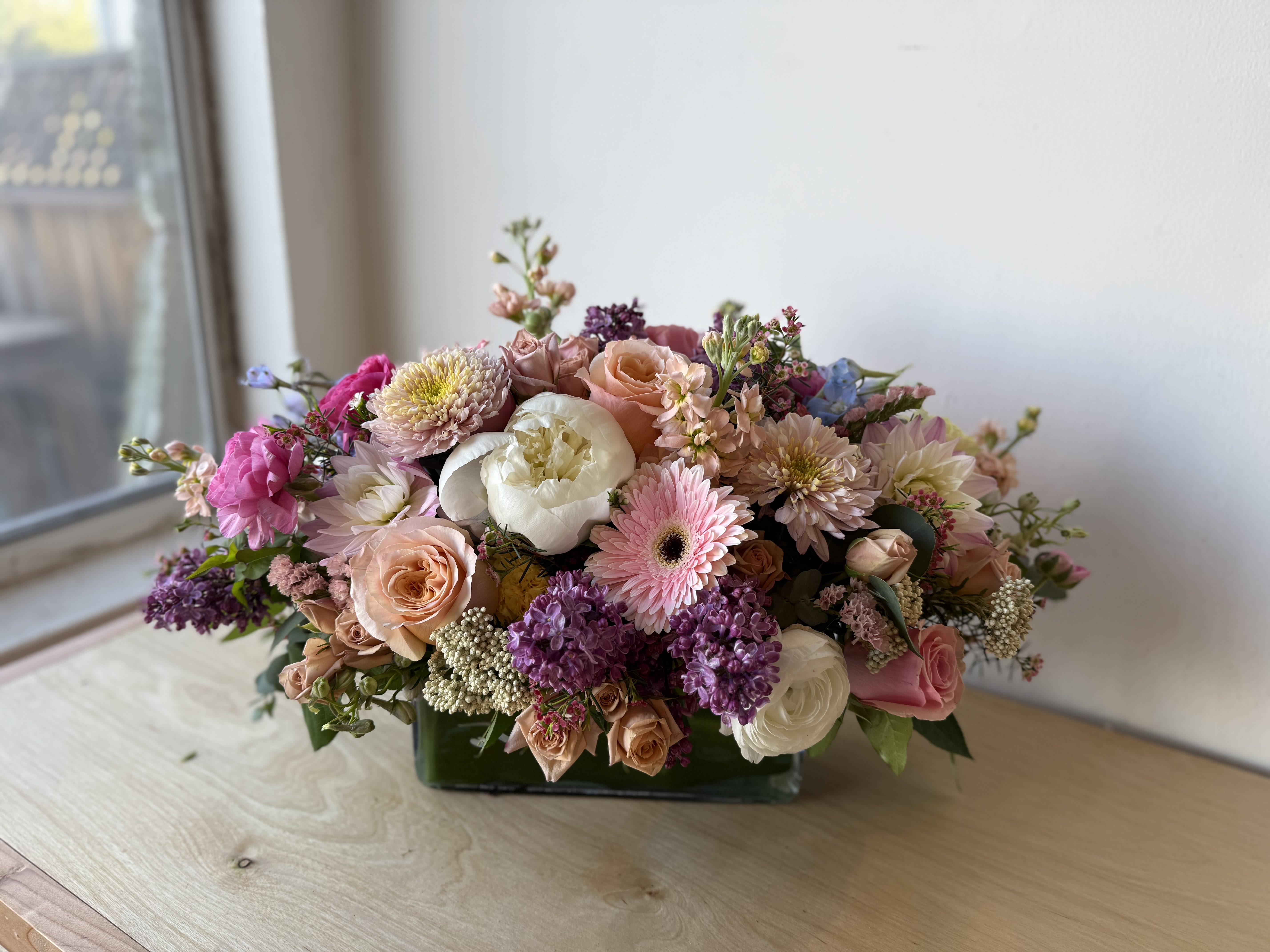 Blooms in May - A lush, garden-style centerpiece that reads like a springtime poem-perfect as a birthday bouquet, anniversary arrangement, or Mother's Day gift. Blooms in May brings together soft pinks, peaches, lavender and creamy whites to create a romantic, celebratory mood that also suits weddings, housewarmings, or a "just because" surprise for the person you're thinking of.
