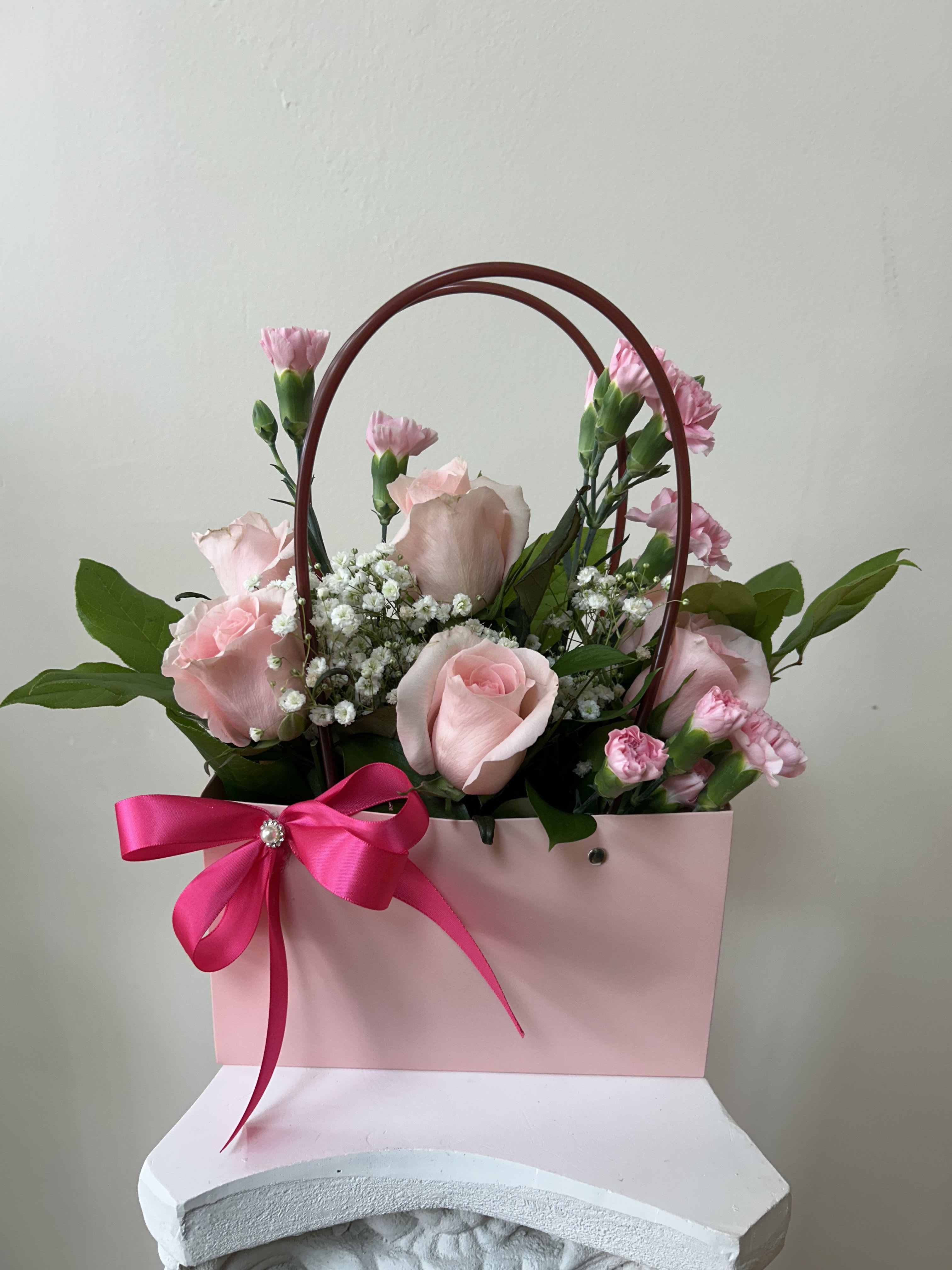 Pink roses and carnations in a pink gift bag with a ribbon bow