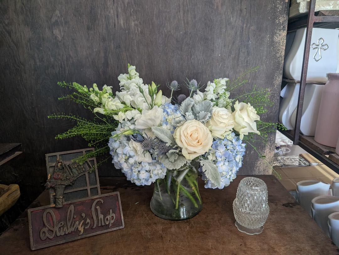 White and pale blue flower arrangement in a glass vase