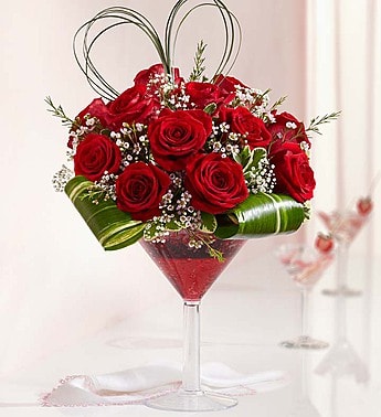Red roses arranged in a martini glass with baby's breath