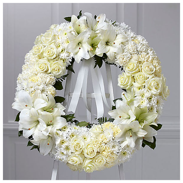 White floral wreath with roses and lilies on a stand
