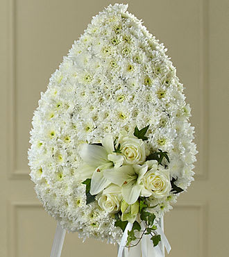 White funeral spray with lilies and roses on an easel