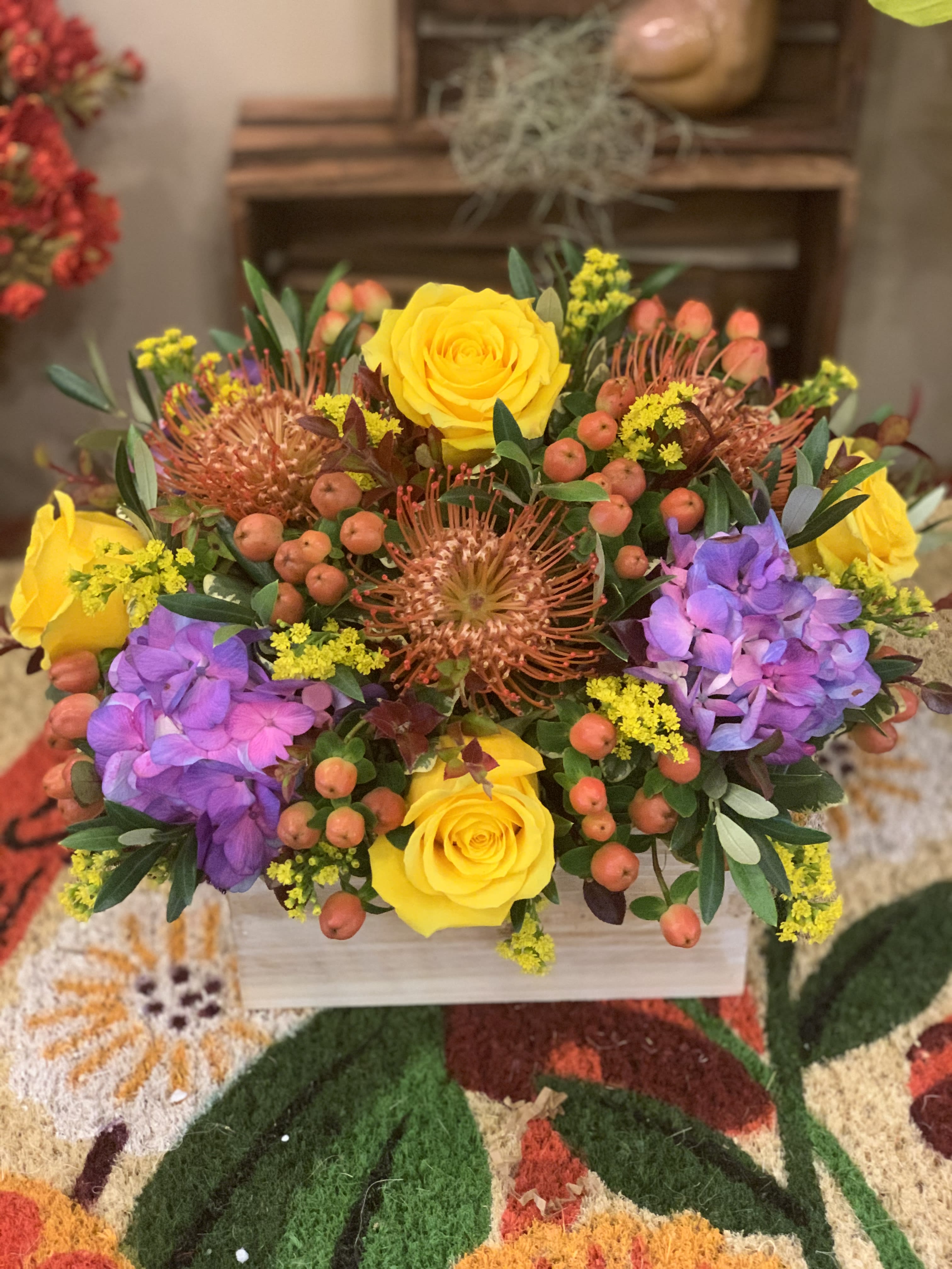 Bright mixed bouquet with yellow roses and purple hydrangeas in a wooden box