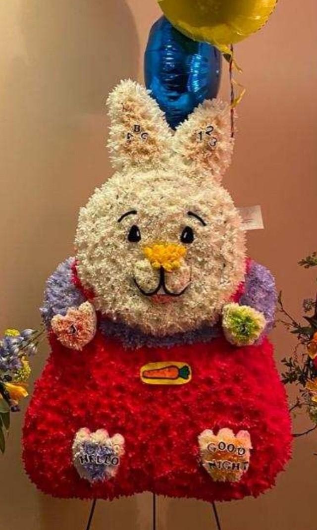 Flower-covered bunny figure with balloons above it