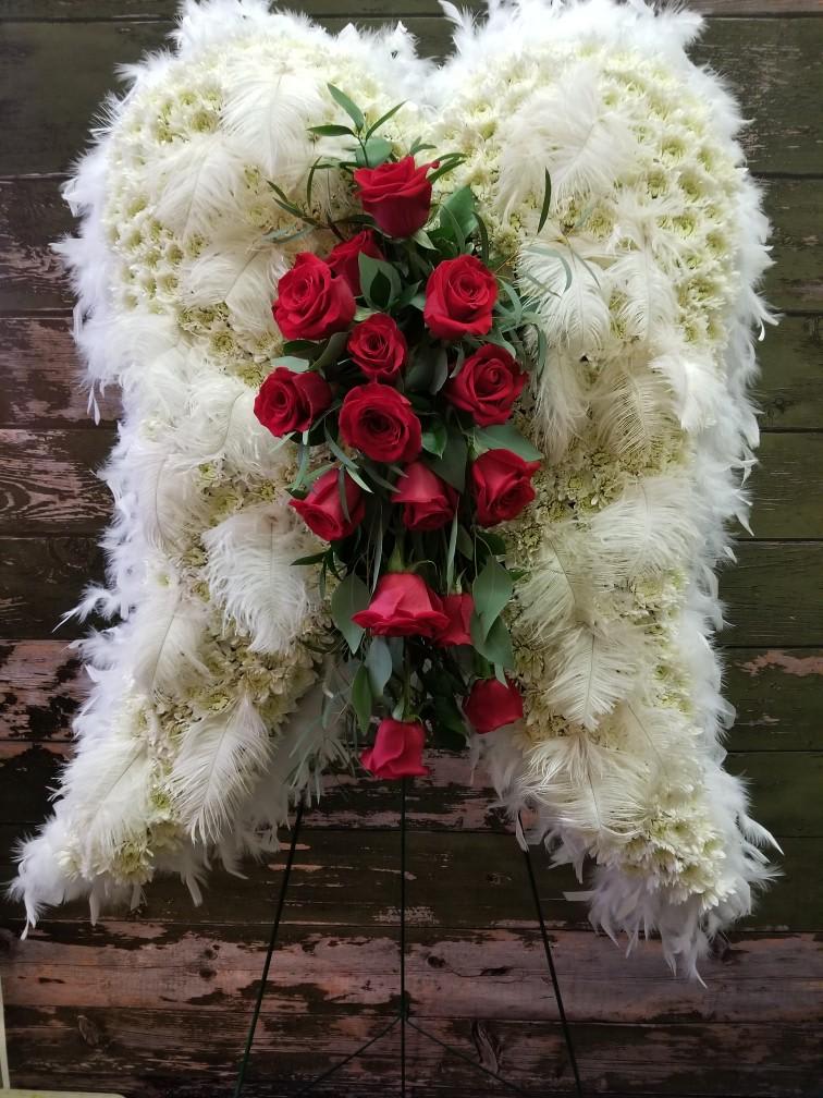 Standing funeral spray of red roses on a white feathered wreath