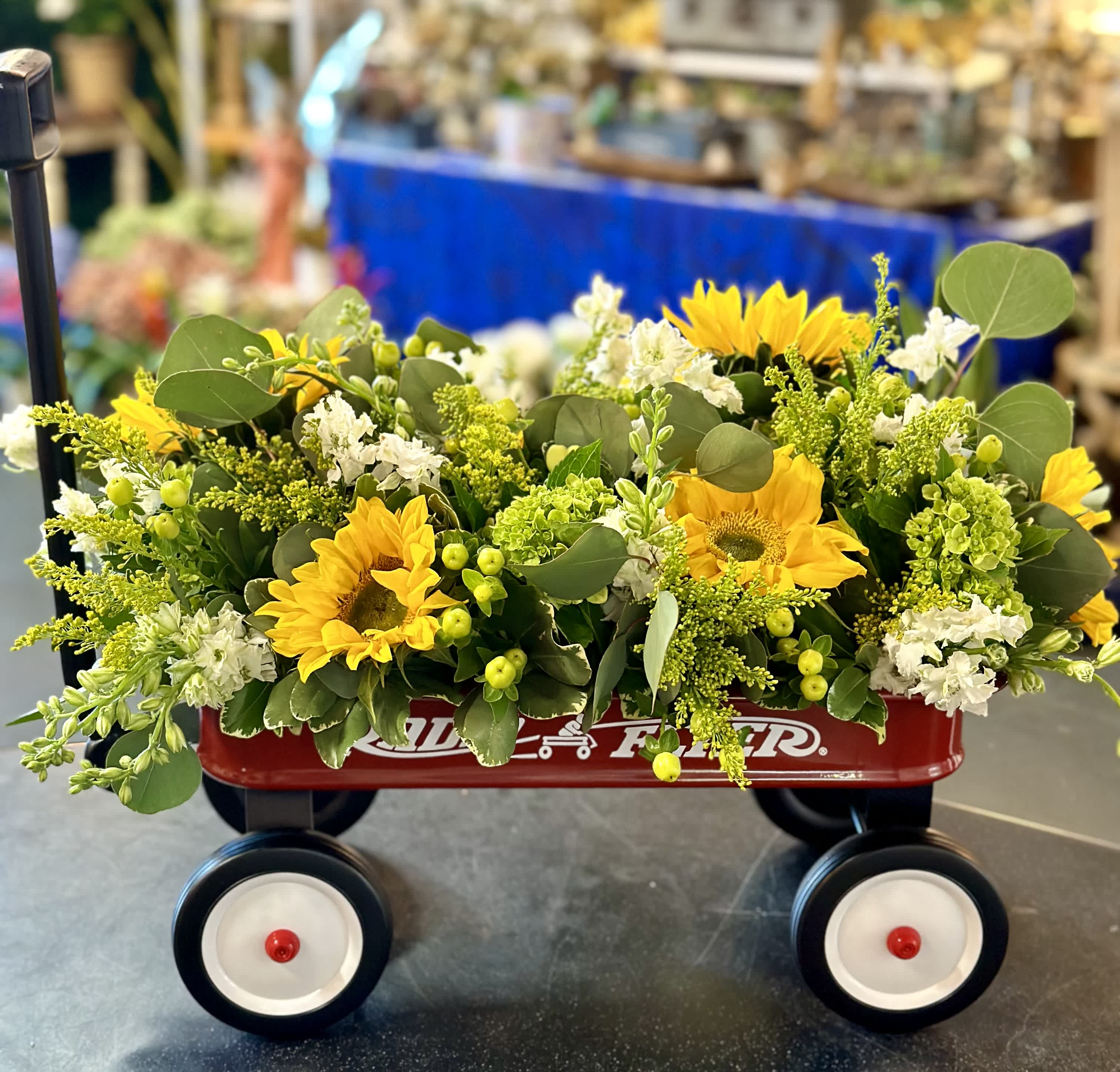 Yellow sunflower arrangement in a red wagon with white flowers