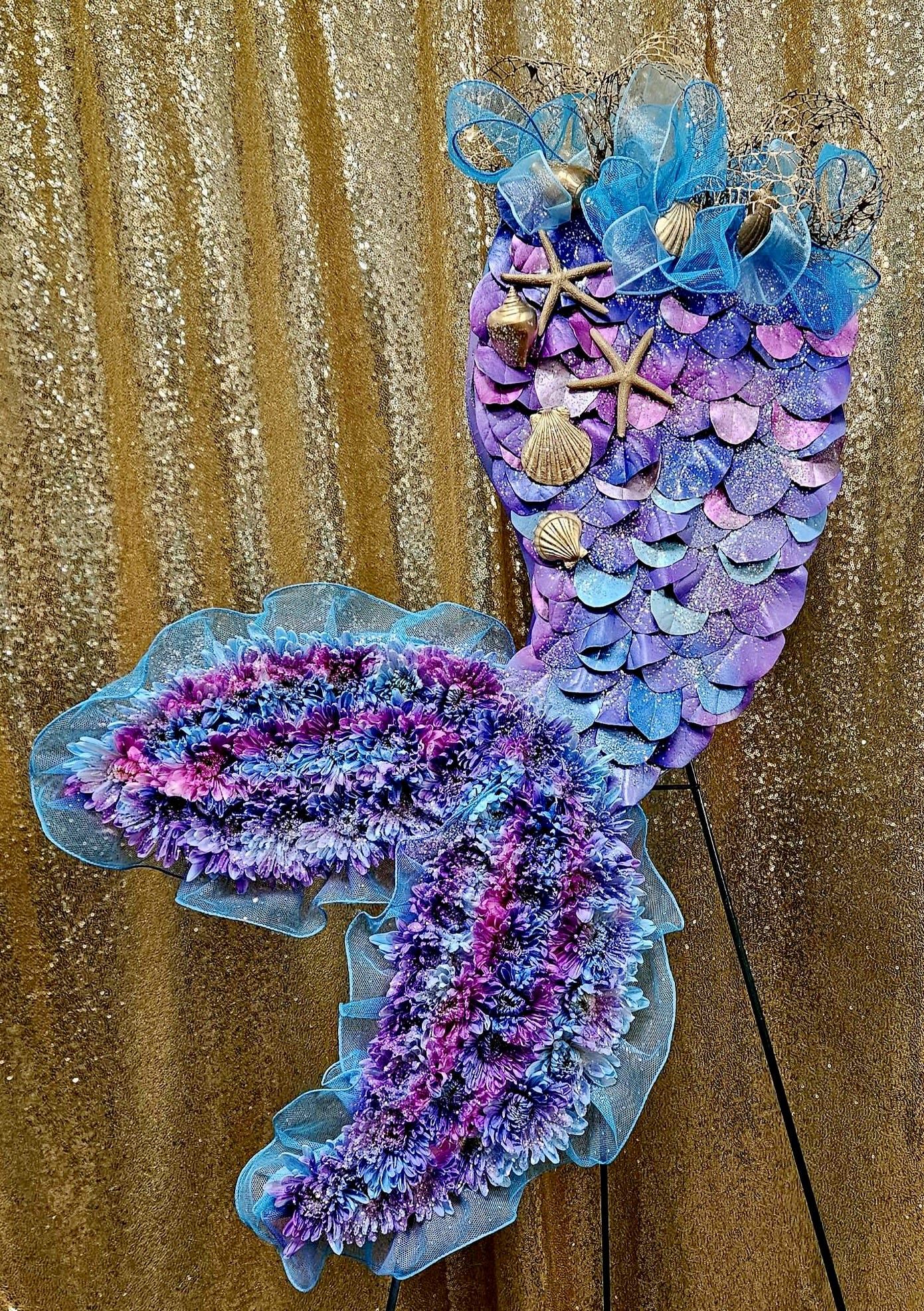 Purple and blue mermaid-shaped floral display with shells and starfish