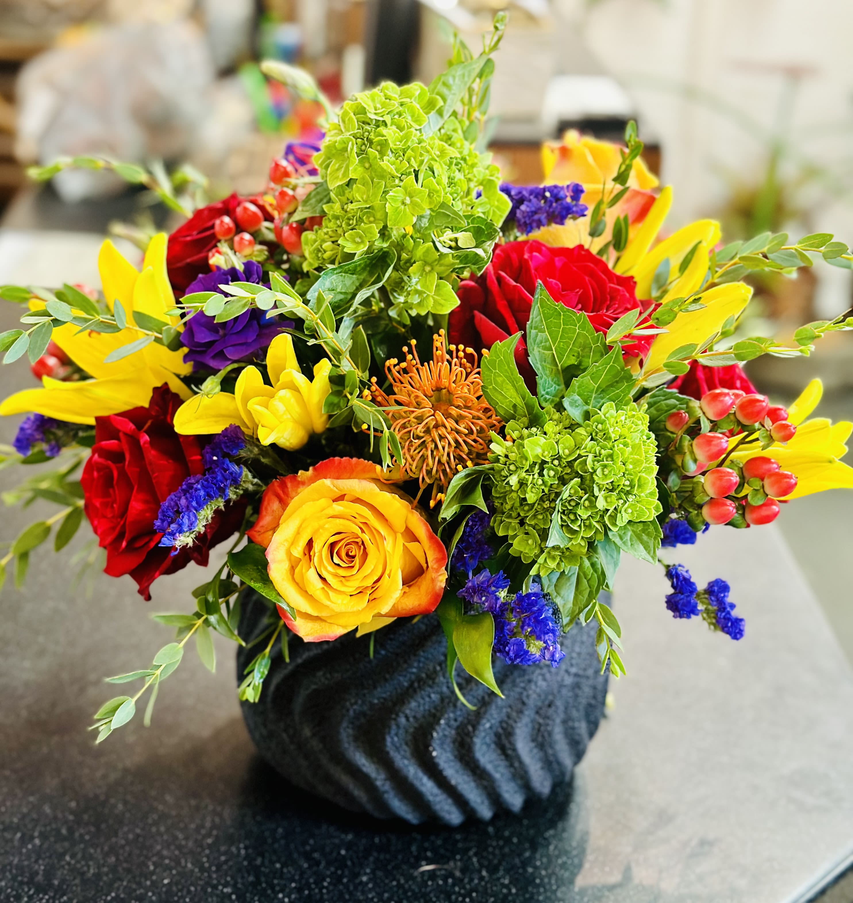 Colorful mixed flower arrangement in a dark textured vase
