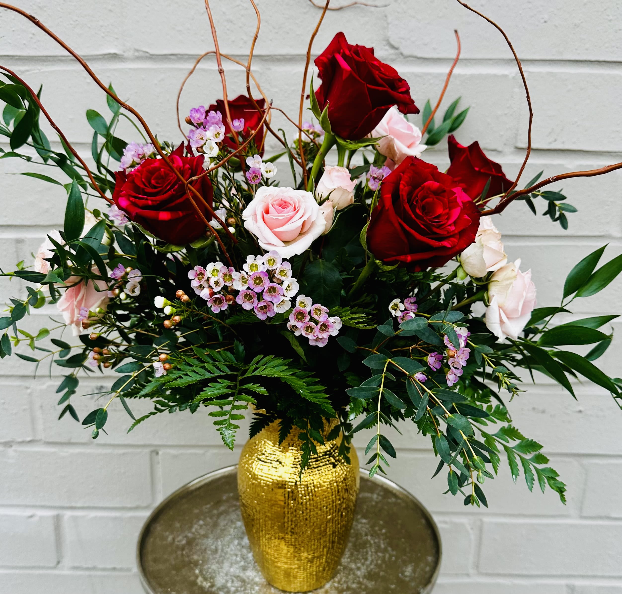 Bouquet of red and pale pink roses in a gold vase
