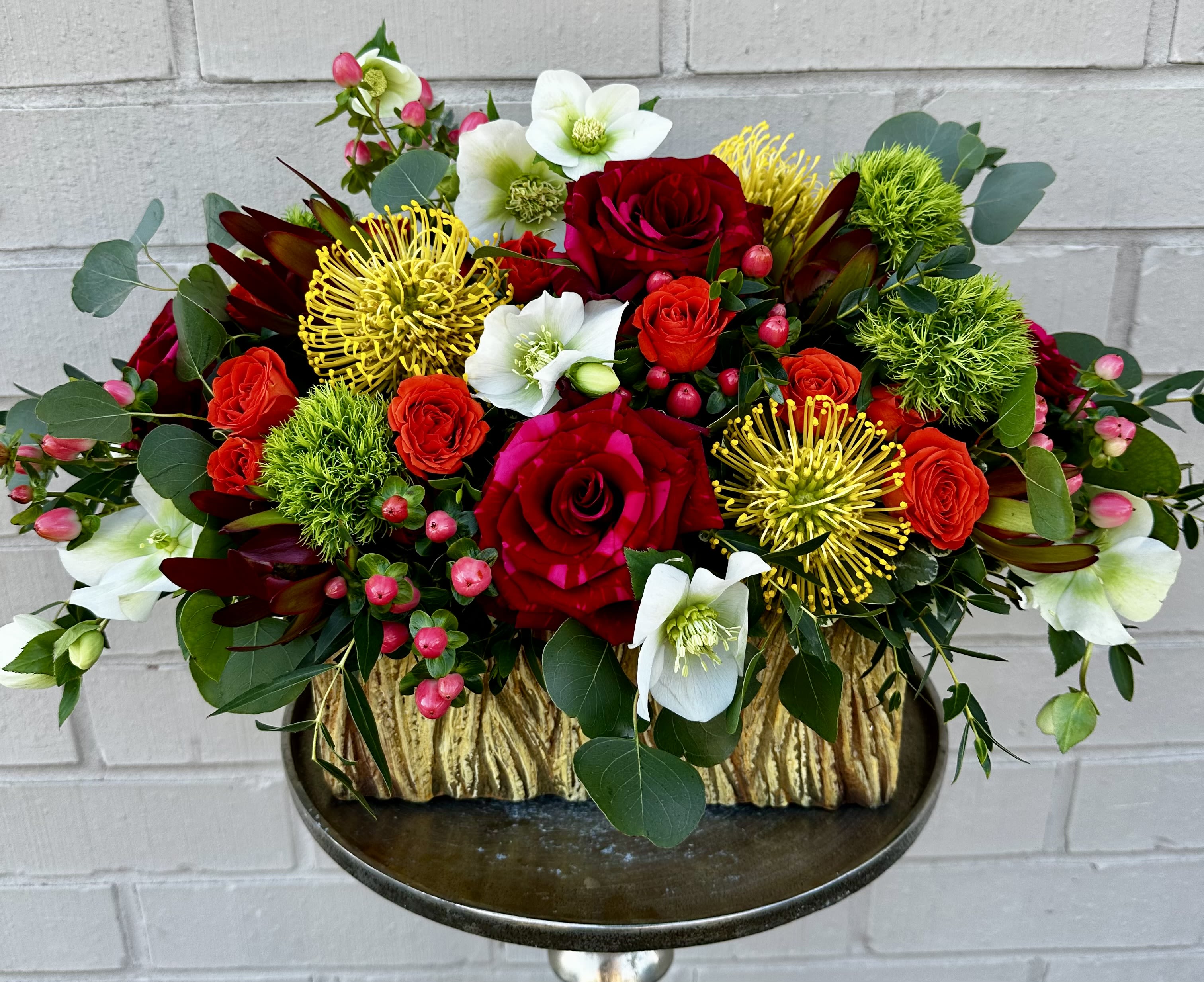 Red roses and white blooms in a gold-textured container