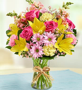 Bouquet of pink and yellow flowers in a clear glass vase