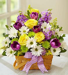 Basket arrangement of yellow roses, purple tulips, and white daisies