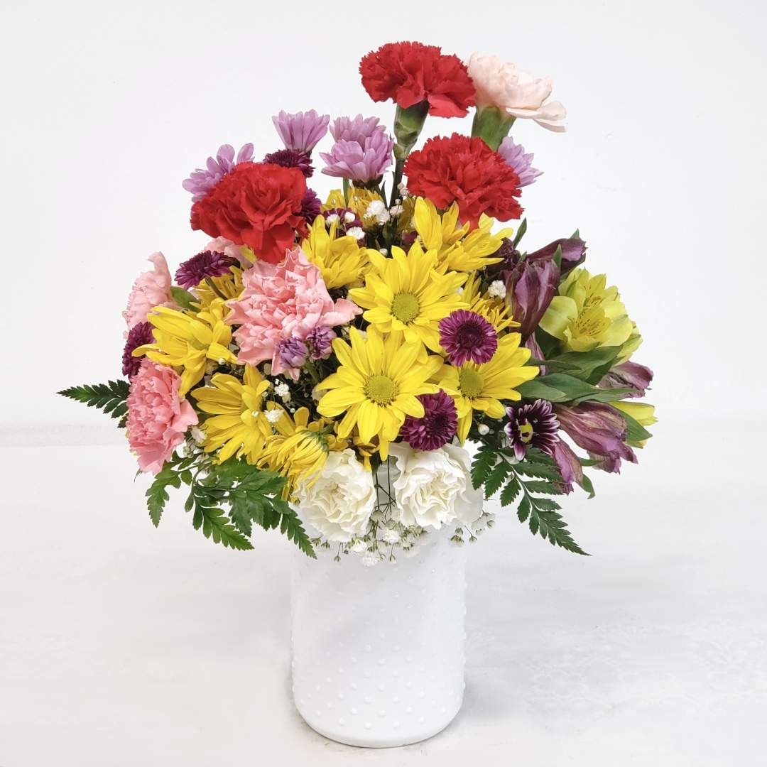 Mixed bouquet of carnations, daisies, and alstroemeria in a white vase
