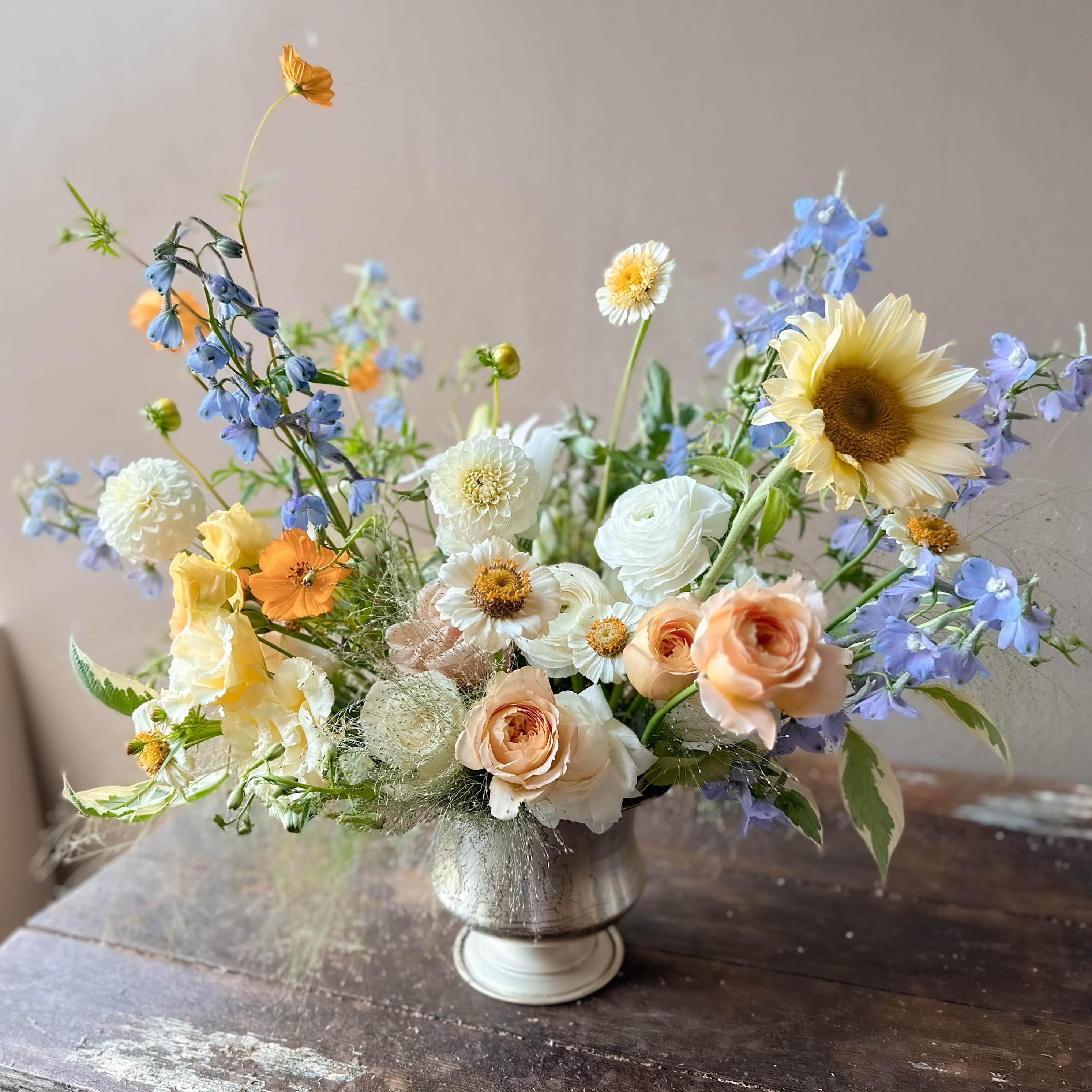 Haeba (Gallery Photo) - Soft tones of creams, yellows and blues with a striking sunflower! Send this beauty to lift your loved one's spirit and let them know how loved they are!
